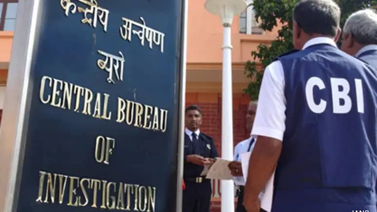सीबीआई के अधिकारी एक बोर्ड के पास खड़े हैं जिस पर "केंद्रीय अन्वेषण ब्यूरो" लिखा है।