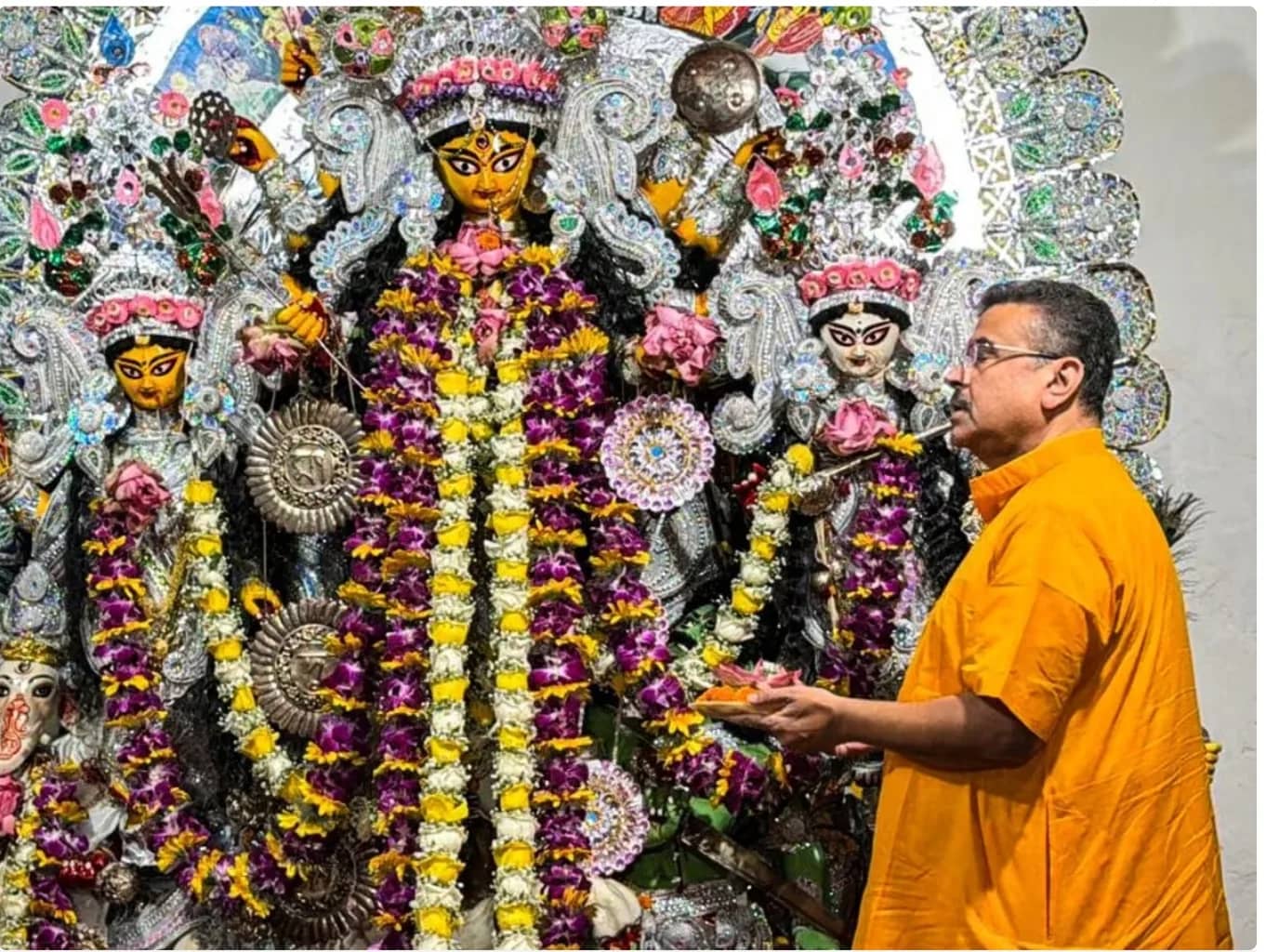 एक आदमी दुर्गा पूजा के दौरान देवी दुर्गा की मूर्ति के सामने पूजा कर रहा है।