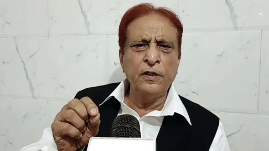 एक व्यक्ति सफेद शर्ट और काले कोट में माइक्रोफोन के सामने बोल रहा है।
