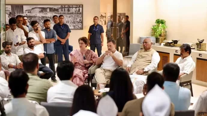 एक कमरे में कई लोग बैठे और खड़े हैं, जिनमें प्रियंका गांधी और राहुल गांधी भी शामिल हैं।