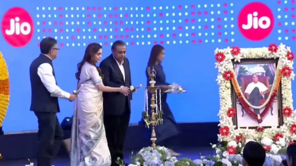 मुकेश अंबानी और नीता अंबानी एक दीया जला रहे हैं, जबकि एक महिला उनके बगल में खड़ी है।
