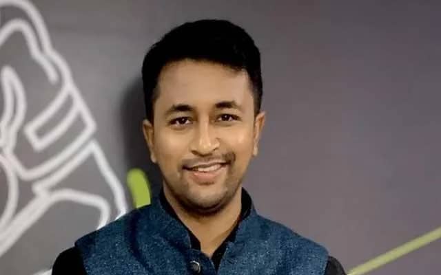 एक आदमी कैमरे की तरफ मुस्कुरा रहा है।